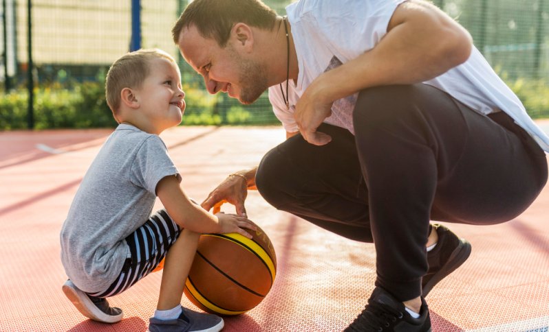 Otec so synčekom hrajú na dvore basketbal.
