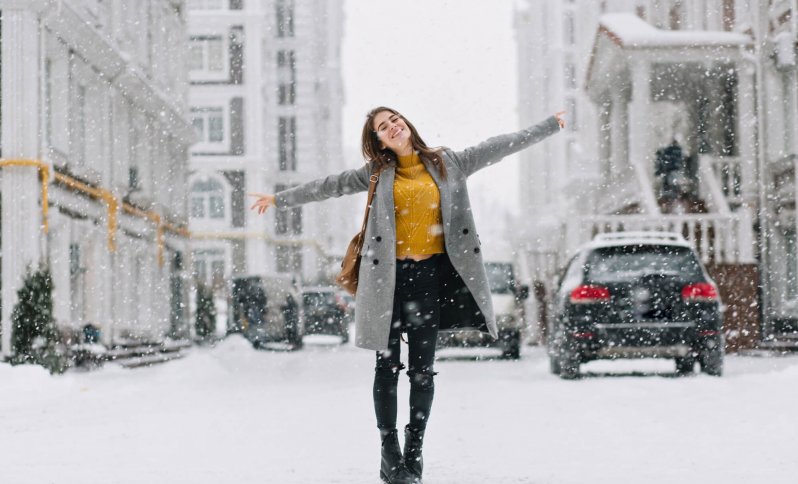 žena v rozopnutom zimnom kabáte, ktorá sa otužuje vonku na ulici